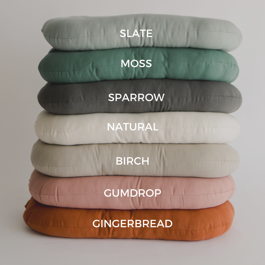 Seven Infant Loungers stacked vertically. Colors shown from top to bottom: Slate, Moss, Sparrow, Natural, Birch, Gumdrop, GIngerbread.